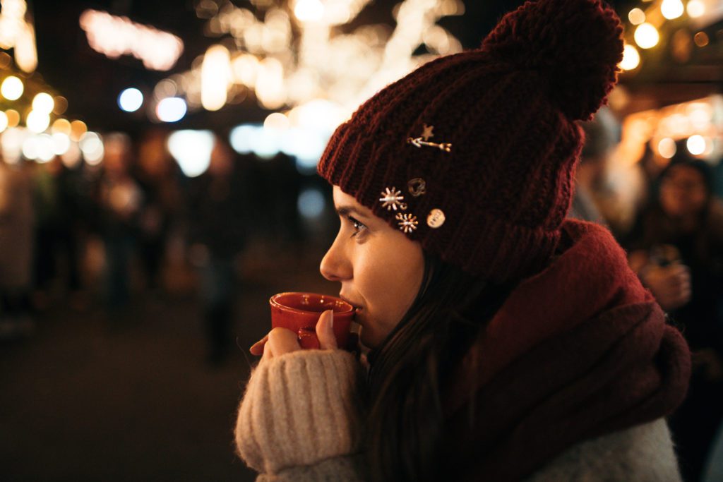 Young girl takes a sip of hot chocolate at the Christmas market